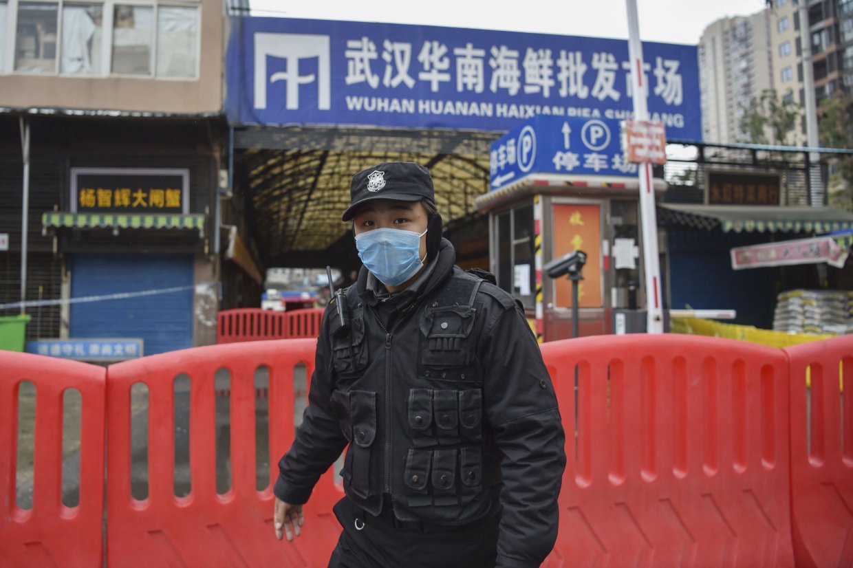 A police officer stands guard on 24 January 2020 outside the Huanan Seafood Wholesale market where the coronavirus was detected in Wuhan, China. At the time, the virus’s death toll stood at 25, rising to more than 816,000 by 25 August. (Hector Retamal/AFP via Getty Images)