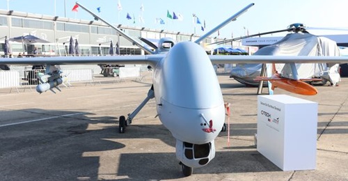 A Turkish Aerospace Anka with a Simsek aerial target mounted on the port wing, model displayed at Paris Air Show 2023.