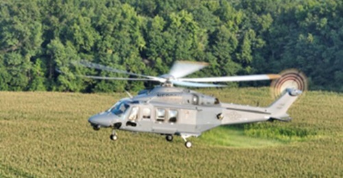 An MH-139A Grey Wolf flies over fields.