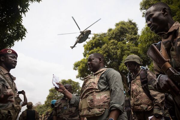 CAR Prime Minister Firmin Ngrébada (centre) talks to troops as a Russian Mi-8AMTSh helicopter flies overhead on the road between Boali and Bangui on 10 January.  (Florent Vergnes/AFP via Getty Images)