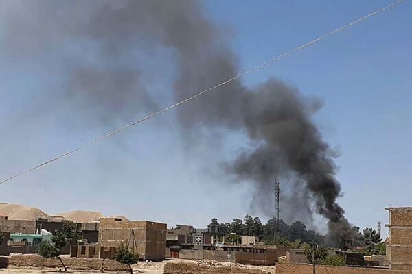 A smoke plume rises from houses in the city of Qala-i-Naw, the capital of Afghanistan's northwestern Badghis Province, amid fighting between ANDSF troops and the Taliban on 7 July. (AFP via Getty Images)