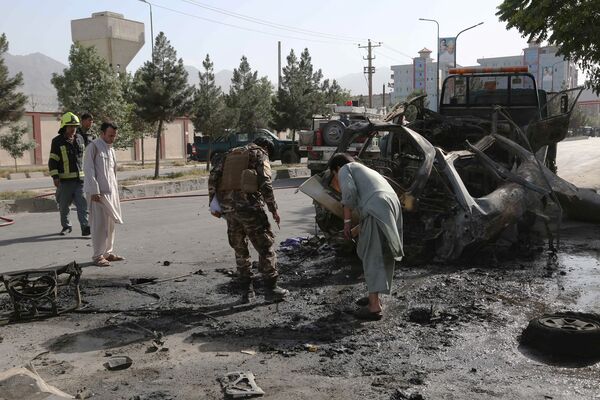 Afghan civilians along with security and emergency personnel inspect the remains of a vehicle at the site of a bomb blast in Kabul on 12 June. UNAMA reported on 26 July that the number of civilian casualties in Afghanistan increased 47% in the first half of 2021 compared with the same period last year. (Zakeria Hashimi /AFP via Getty Images)
