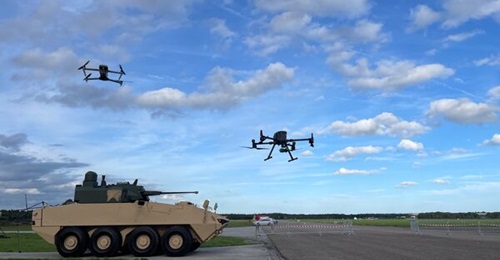 An Autel Evo Max UAV and a DJI Matrice quadcopter flying above a General Dynamics Land Systems LAV700 vehicle at C-UAS TIE23.