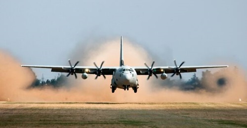 A Lockheed Martin C-130J-30 transport aircraft performs a tactical take-off from an unprepared runway.