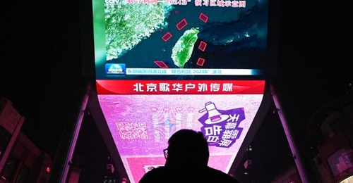 A man watches a news programme about Chinese military drills surrounding Taiwan on a giant screen outside a shopping mall in Beijing on 14 October 2024.