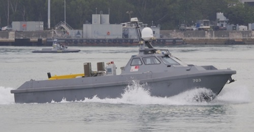 The mine detection variant of the Venus 16 unmanned surface vehicle leaving harbour for sea trials. The in-service Protector unmanned surface vehicle can be seen in the background.