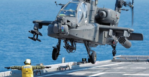 A US Army AH-64D Apache helicopter prepares to land aboard USS 
        
         during an exercise. With an increasing emphasis on maritime operations for the helicopter, the service is to fit an emergency underwater crew escape system.