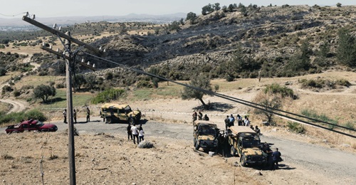 Members of the northern Cypriot security forces stand on a burnt portion of a slope where, according to officials, a suspected Russian-built missile exploded overnight on 1 July during an Israeli aerial raid in Syria.
