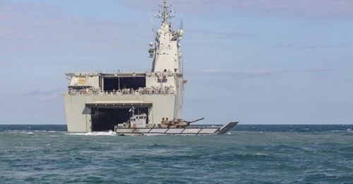 An LCM-1E landing craft embarked with an Australian Army M1A1 main battle tank, leaving the well dock of HMAS 
        
        .