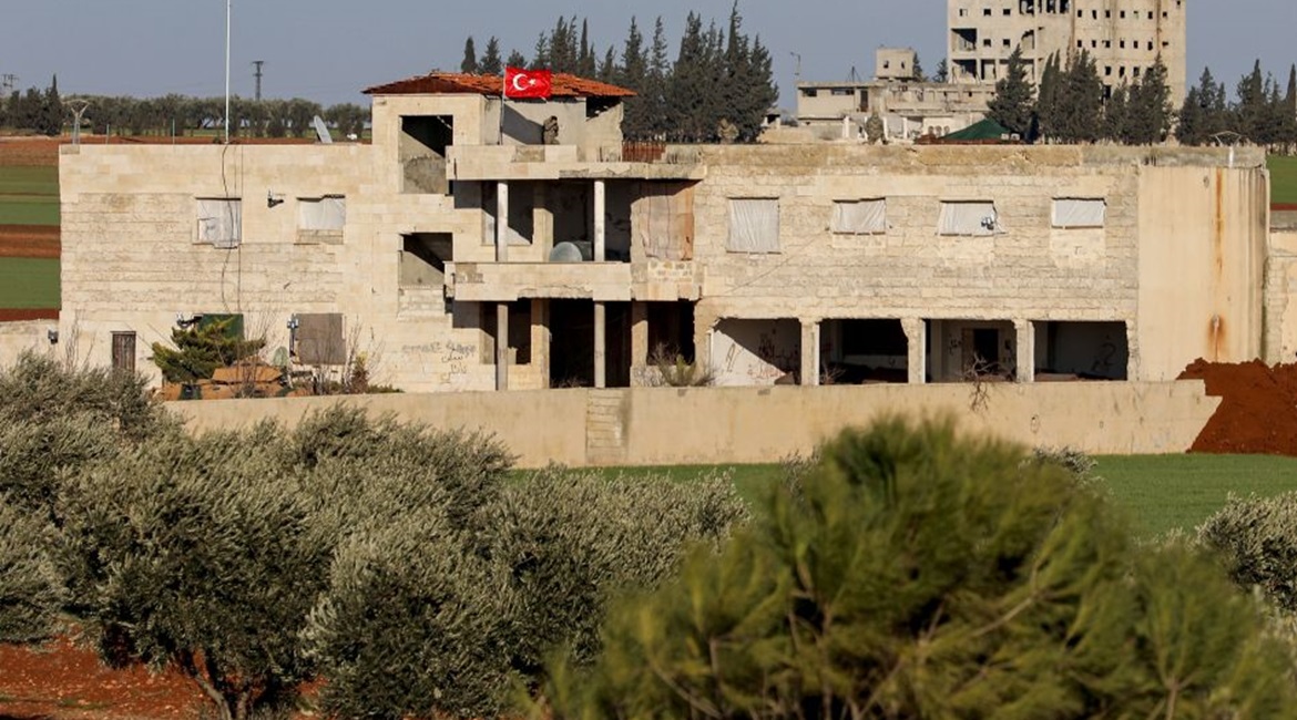 A Turkish flag flies over a building with a Turkish armoured vehicle parked outside north of Saraqib on 1 February.