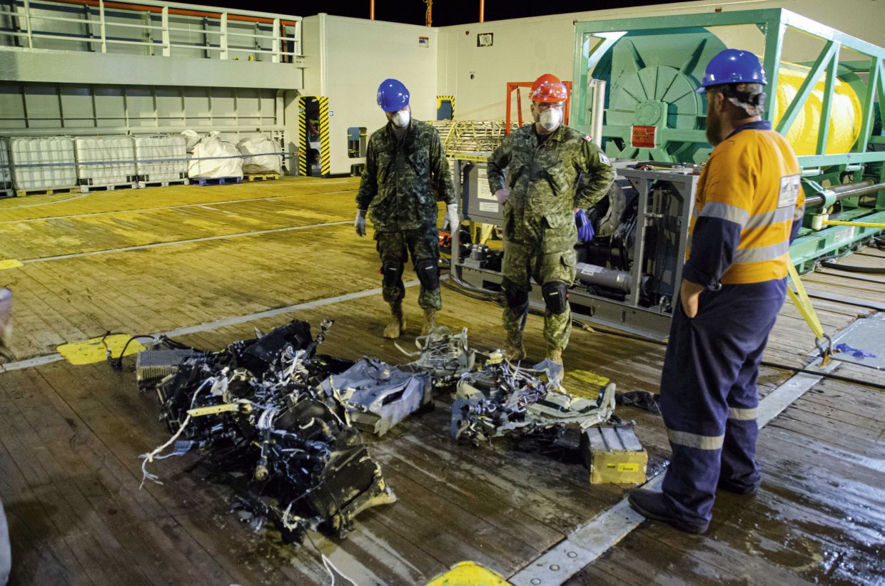 Canadian Armed Forces members and EDT Hercules personnel inspect recovered parts of CH-148 Cyclone on 31 May 2020 during recovery operations for the aircraft.