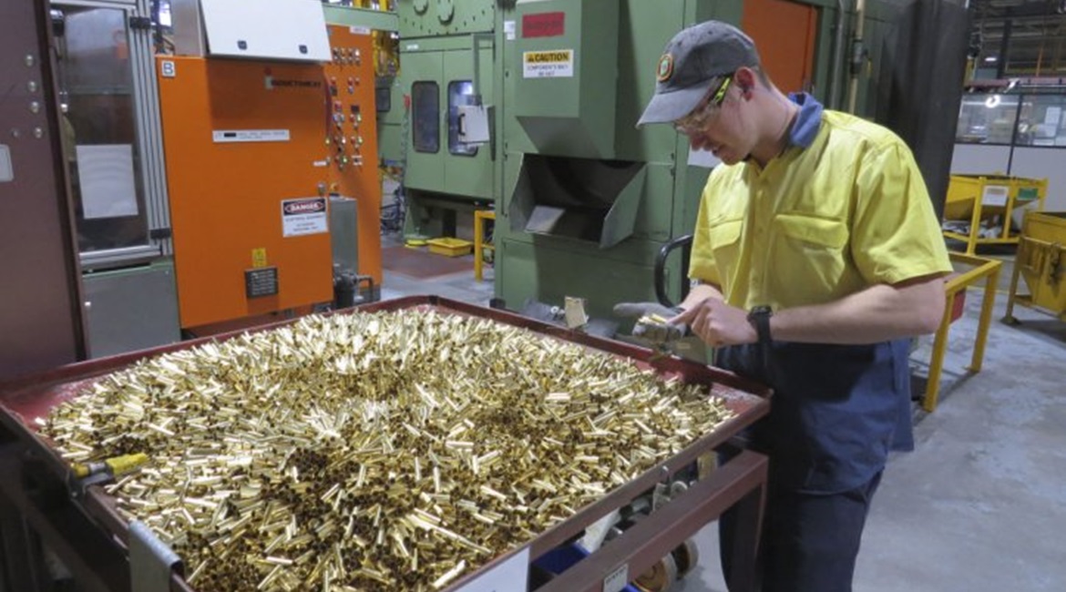 Patrick Warner, an employee at Thales Australia, examines cartridge cases for 5.56 mm ammunition, part way through the manufacturing process at the Benalla, Victoria, production line.