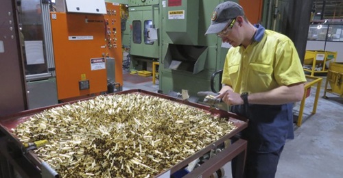 Patrick Warner, an employee at Thales Australia, examines cartridge cases for 5.56 mm ammunition, part way through the manufacturing process at the Benalla, Victoria, production line.