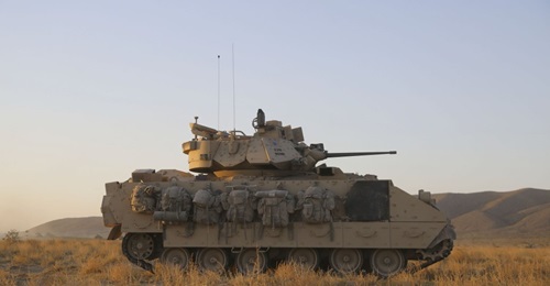 An M2A2 Bradley observes the terrain for enemy elements during training at Fort Irwin, California, in May 2018. The US Army has tasked BAE Systems with refitting two A2 Bradley vehicles with hybrid electric drives.