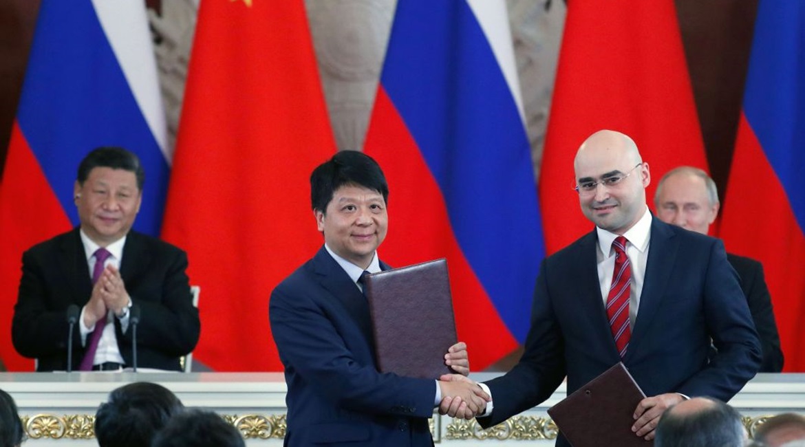 Chinese President Xi Jinping (left, rear) and Russian President Vladimir Putin (right, rear) applaud as Guo Ping (centre), Deputy Chairman of the Board and Rotating Chairman of Huawei, shakes hands with Alexei Kornya, President and CEO of Russian mobil...