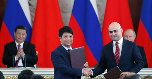 Chinese President Xi Jinping (left, rear) and Russian President Vladimir Putin (right, rear) applaud as Guo Ping (centre), Deputy Chairman of the Board and Rotating Chairman of Huawei, shakes hands with Alexei Kornya, President and CEO of Russian mobil...