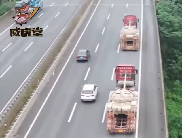 A screenshot from CCTV 7 footage released on 17 November showing two modified civilian flatbed trucks on a Chinese road transporting PLAGF Type 59D MBTs. (CCTV)