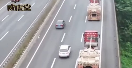 A screenshot from CCTV 7 footage released on 17 November showing two modified civilian flatbed trucks on a Chinese road transporting PLAGF Type 59D MBTs.