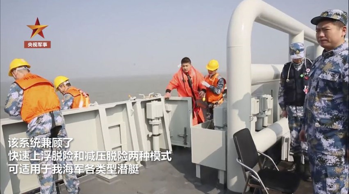 A screengrab from CCTV footage released on 2 January showing submariner boarding a support vessel after recovery from a life raft, wearing new escape suit. The image also shows a yellow hood inflation connector.