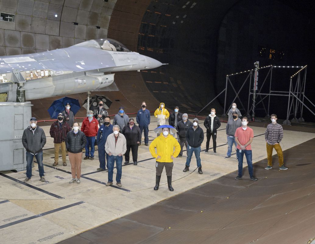 The test team for the F-16 canopy water pooling visibility test stand beside the test article in the National Full-Scale Aerodynamics Complex’s 12x24 m test section on 1 December 2020. The USAF used the wind tunnel to test how to address rain pooling on the aircraft’s canopy and reducing pilot visibility. (NASA)
