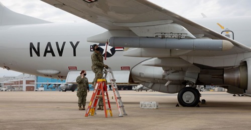 A member of the Air Test and Evaluation Squadron (VX) 20 puts a pod-mounted radio frequency countermeasure system on a P-8A Poseidon.