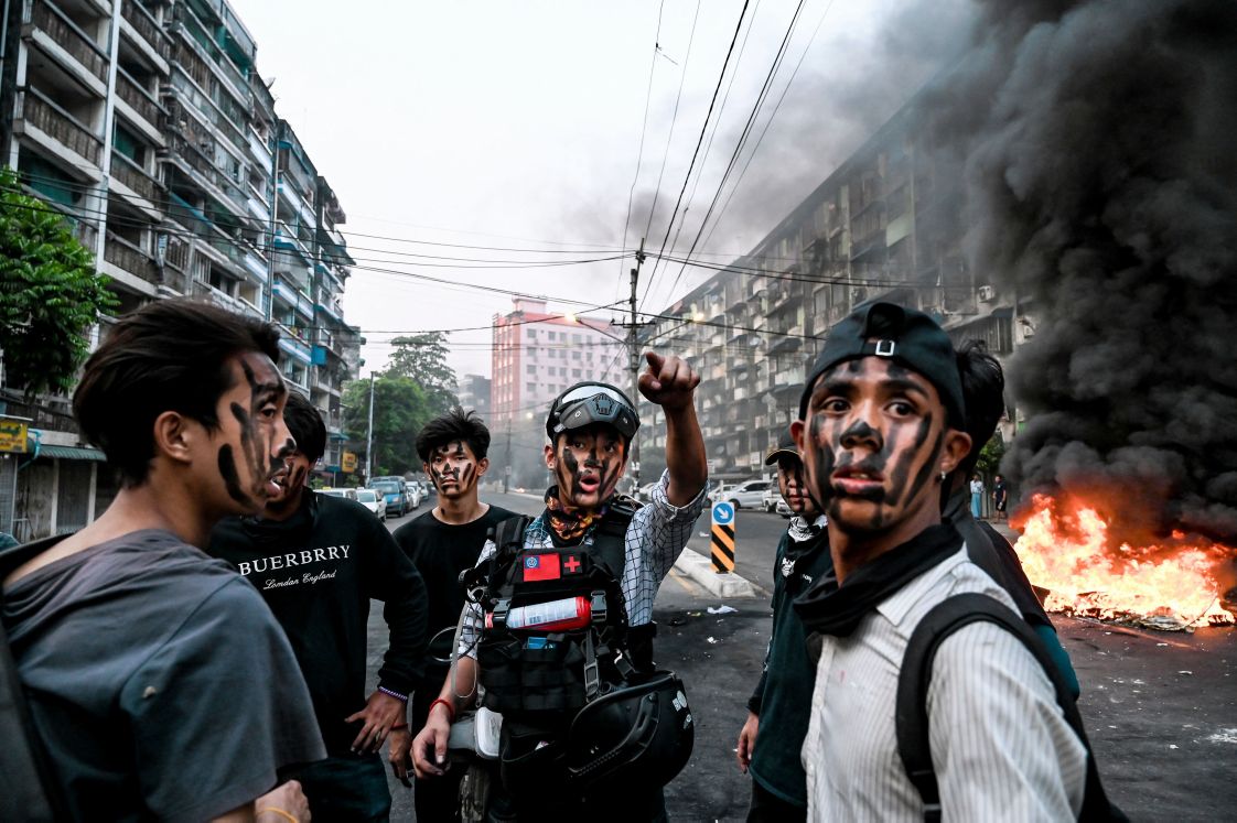 Protesters with their faces painted stand near a burning makeshift barricade in Yangon on 30 March 2021 during a protest against the military coup. Security forces opened fire on protesters in Bago on 9 April, killing at least 82 people. (STR/AFP via Getty Images)