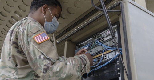 A US Army specialist with the 1st Armored Division Combat Aviation Brigade uses a Category 5 cable to establish a network connection at Camp Atterbury Joint Maneuver Training Center in Indiana.